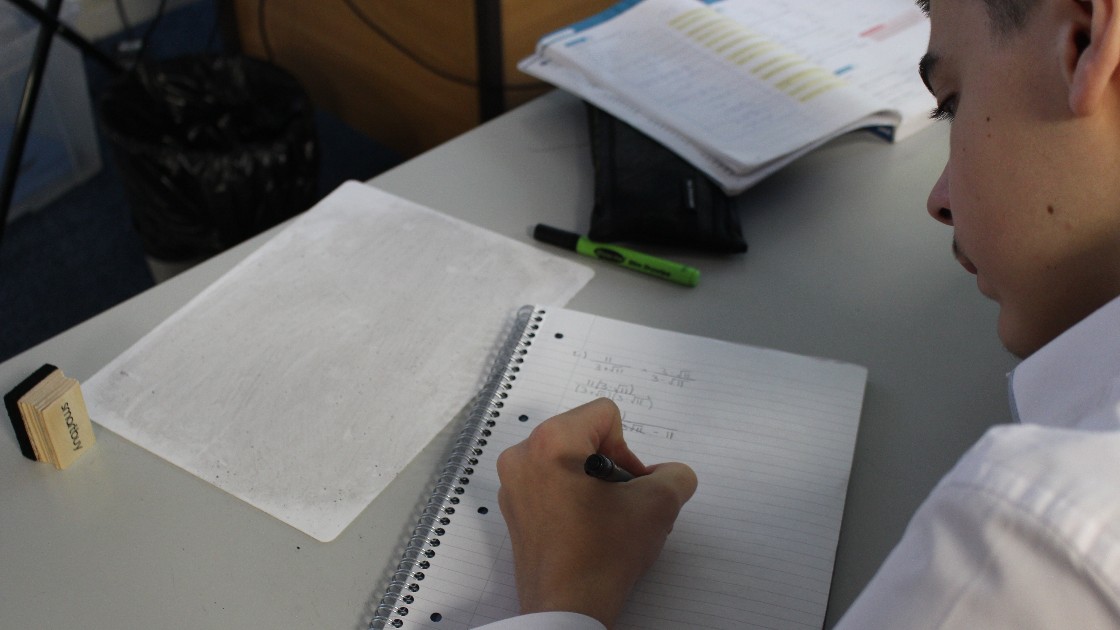 Student writing in a notebook during a maths lesson