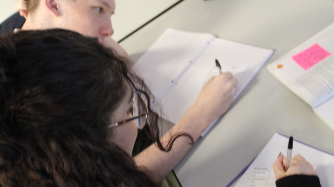 Students writing in notebooks during a lesson