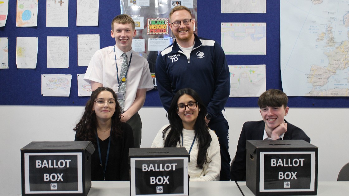 Students and a teacher with ballot boxes in a classroom
