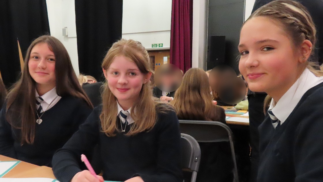 Students at tables during anti-bullying trip workshop, writing on worksheets