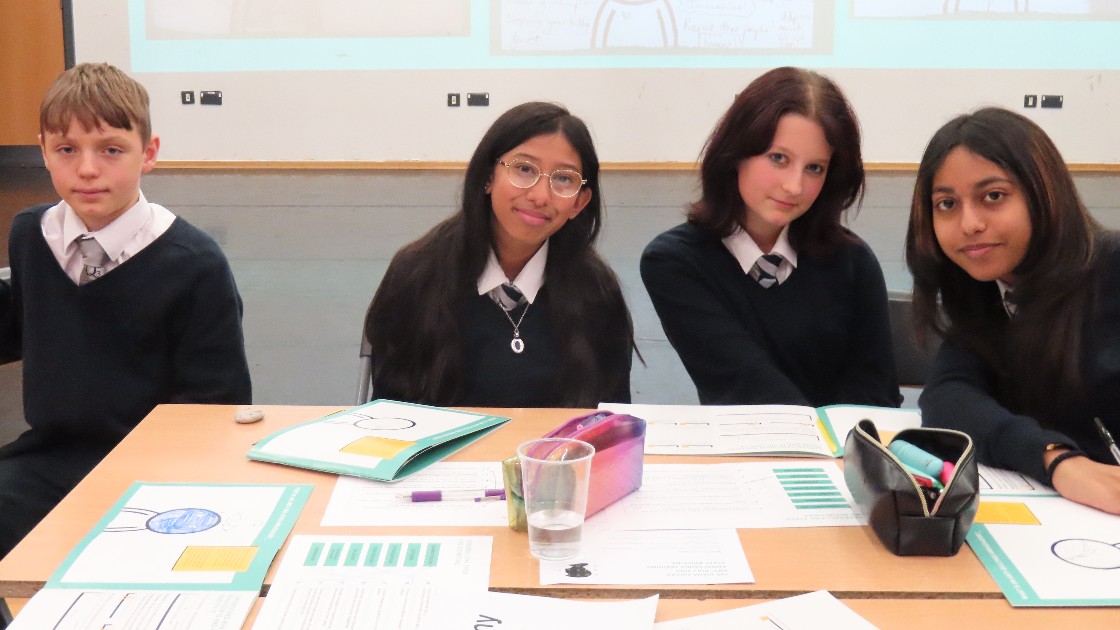 Students in uniform at a workshop table during an anti-bullying trip, working with worksheets and booklets