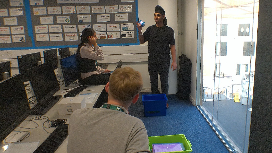 Students in a Computing lesson testing small robots with a teacher supervising