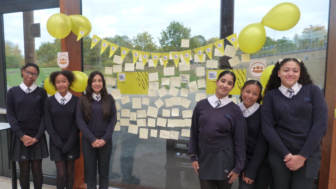 Students standing by a Values Reflection display with balloons and sticky notes