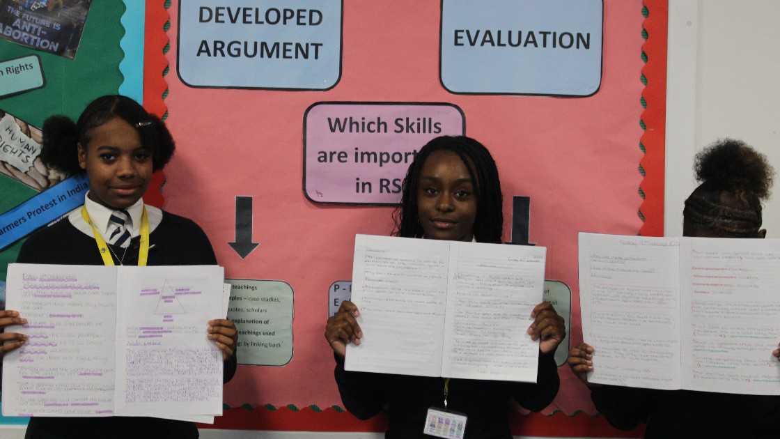 Students in RS holding written work in front of a classroom display about skills