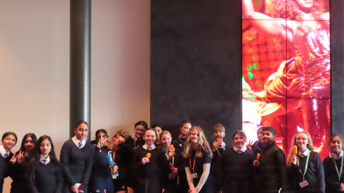 Students at the theatre, posing in uniform by a show display